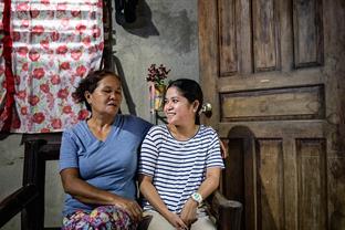 April sits in her home with her mother