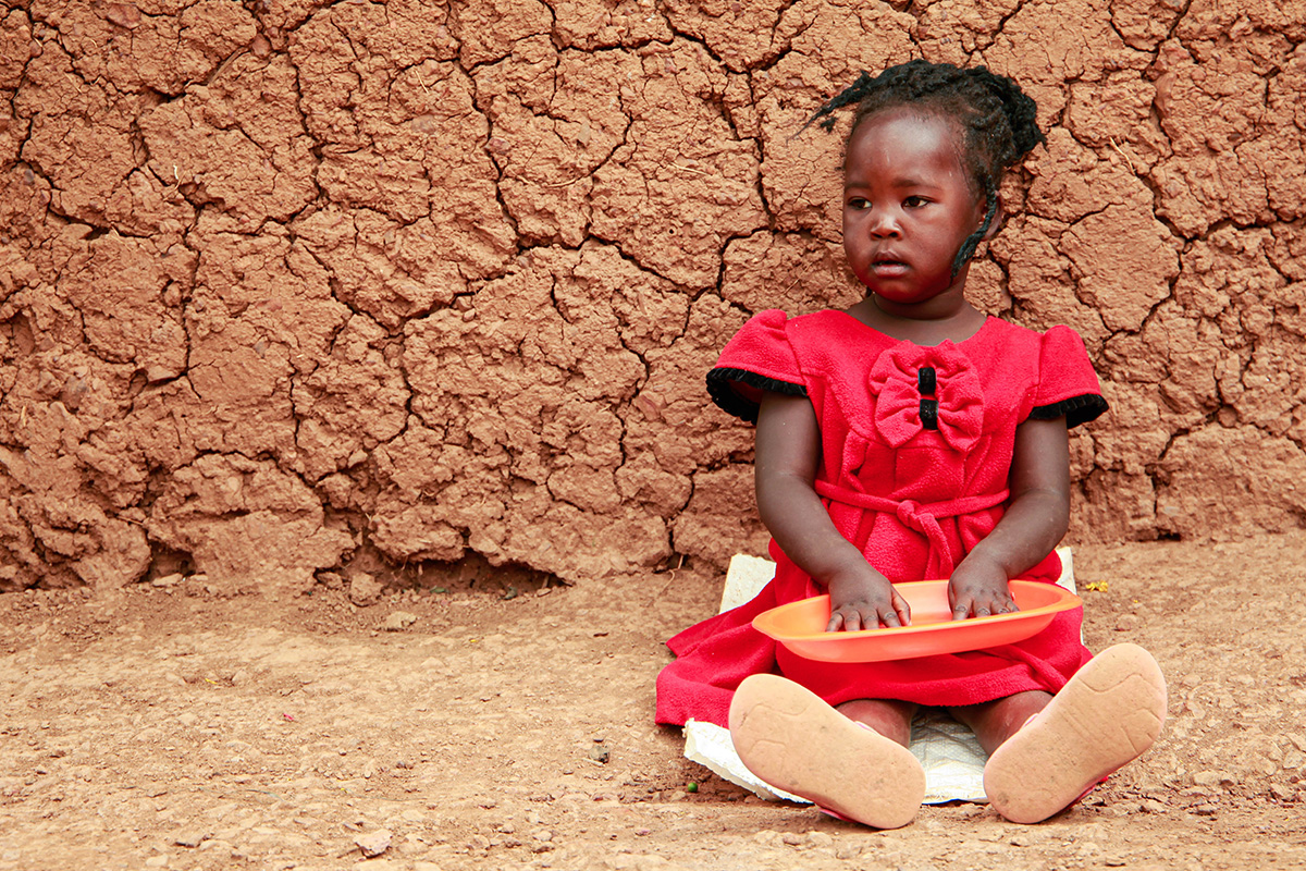 a little girl sits on the ground holding an empty plate