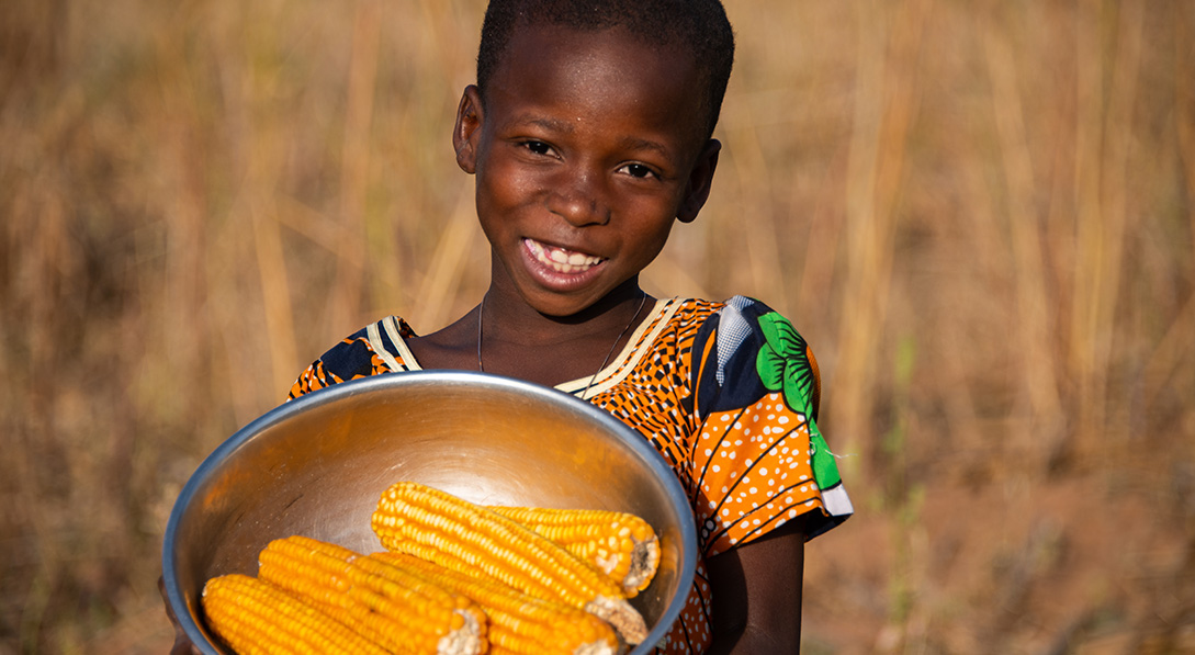 a girl holds a bowl of corn