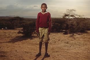 a boy stands in a desert