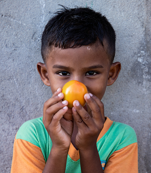 a boy holds a tomato