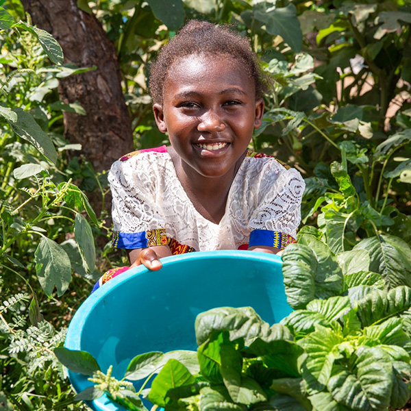 a girl holds a basket of vegetables