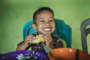 a boy smiles while he eats