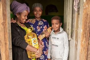Zere and her children hold food given by the center