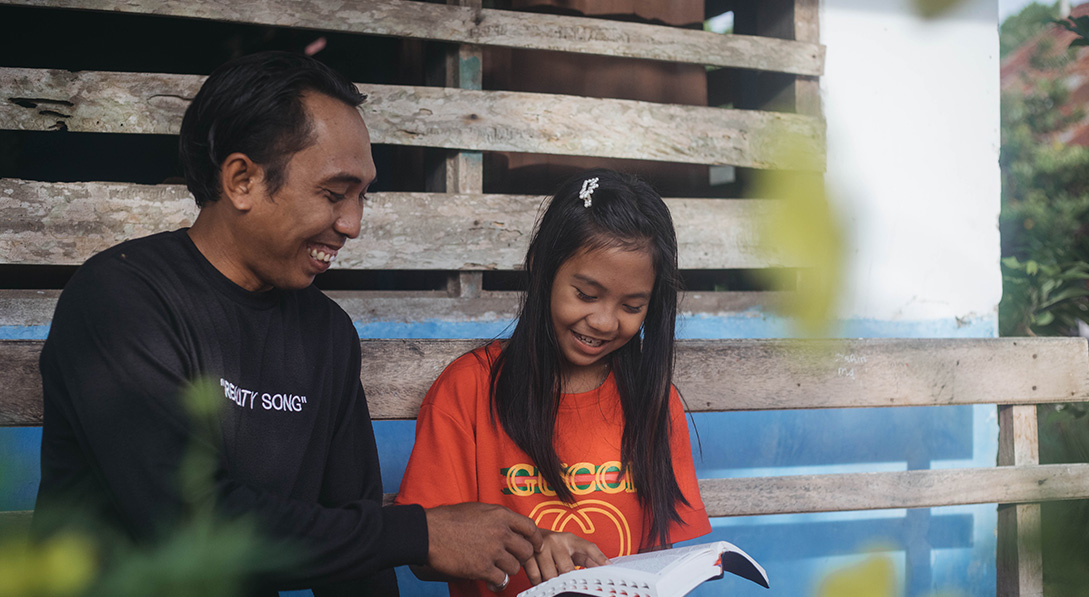 a father and daughter read the Bible together