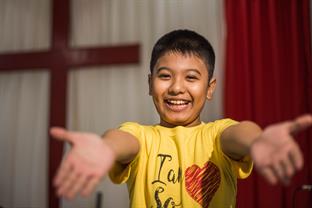 a boy smiles and reaches out his arms