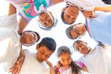 a group of older children pray together