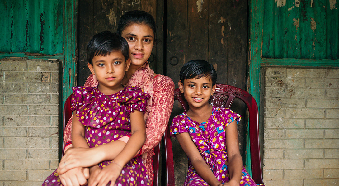 3 sisters sit together in front of their home