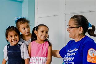 a Compassion staffer sits with 3 girls