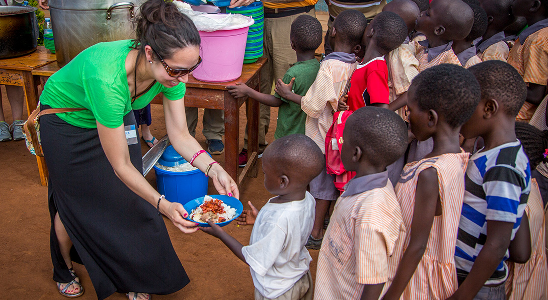 a woman hands out food to children