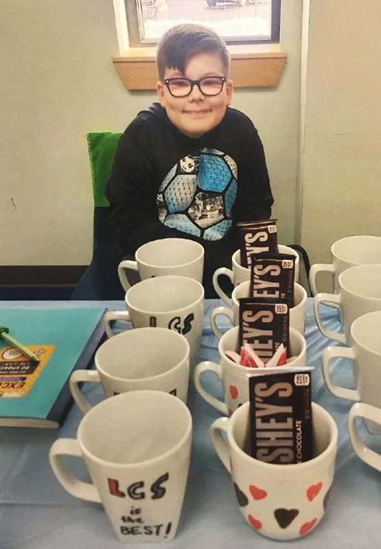 Samuel with a group of mugs that he's made