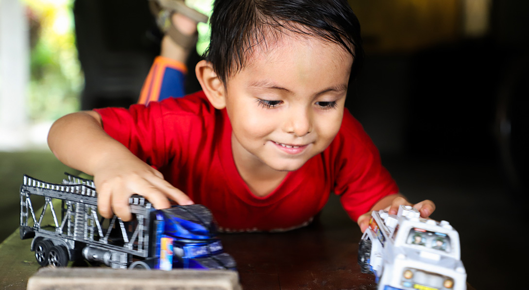 a young boy plays with toy cars