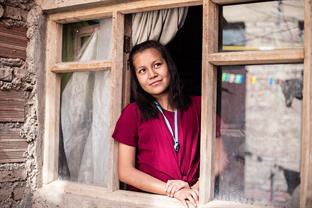 a girl looks out of a window in her home