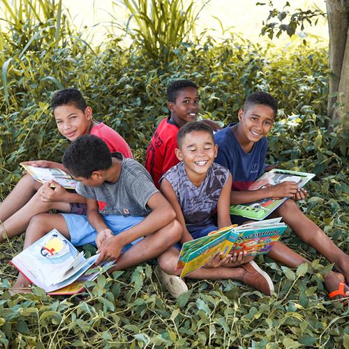 several boys reads books under a tree