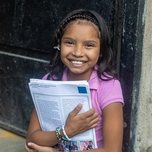 a girl holds letters from her sponsor
