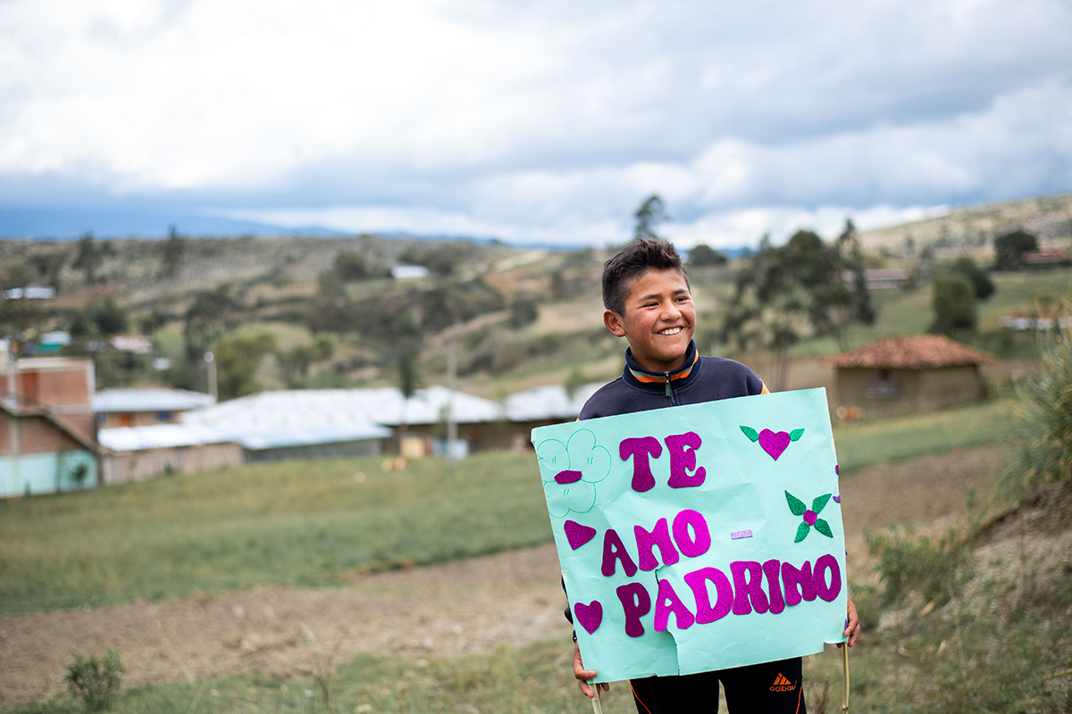 a boy holds a sign that says "Te Amo Padrino"