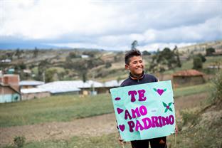 a boy holds a sign that says "Te Amo Padrino"
