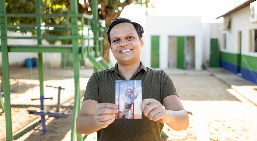 Eraldo holds a picture of himself as a child in the sponsorship program.