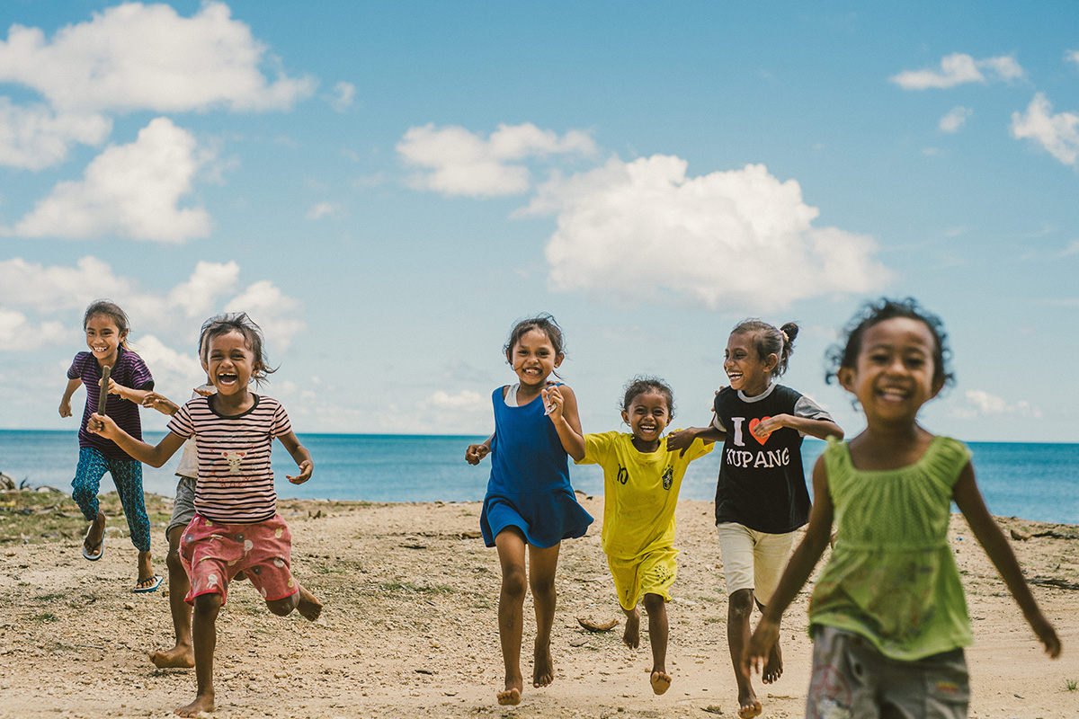 a group of children runs on the beach