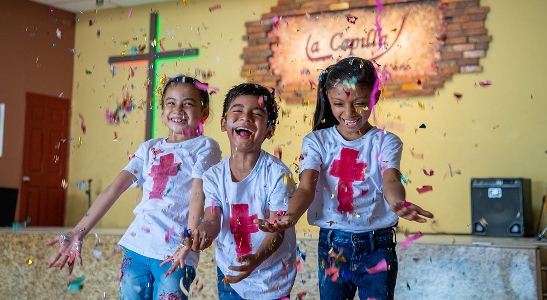 3 children laugh as confetti falls