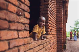 a boy smiles and leans out of a window