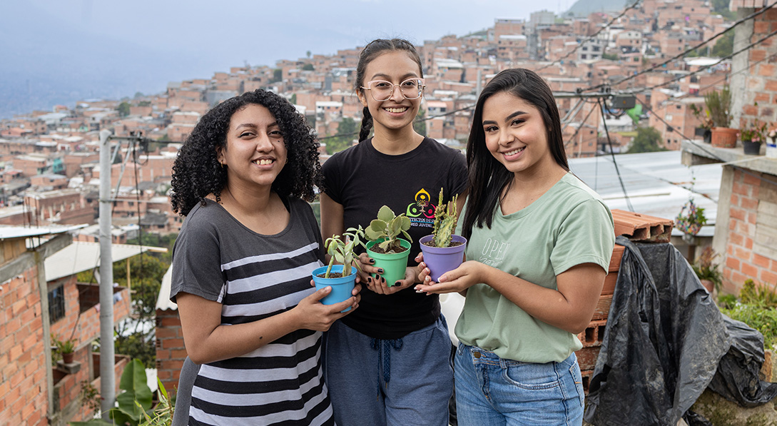 3 teenage girls hold plants