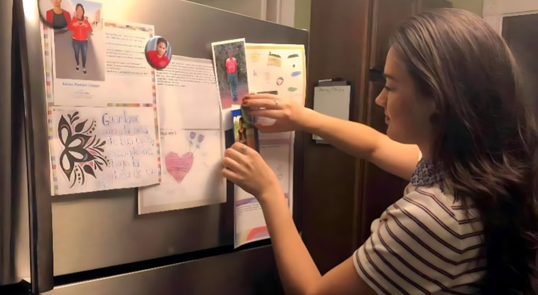 a girl puts her sponsor child's photo on her fridge