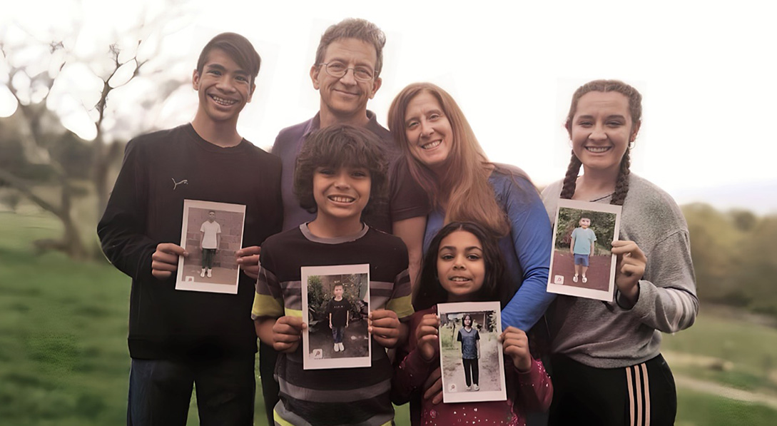 a family holds photos of their sponsored children