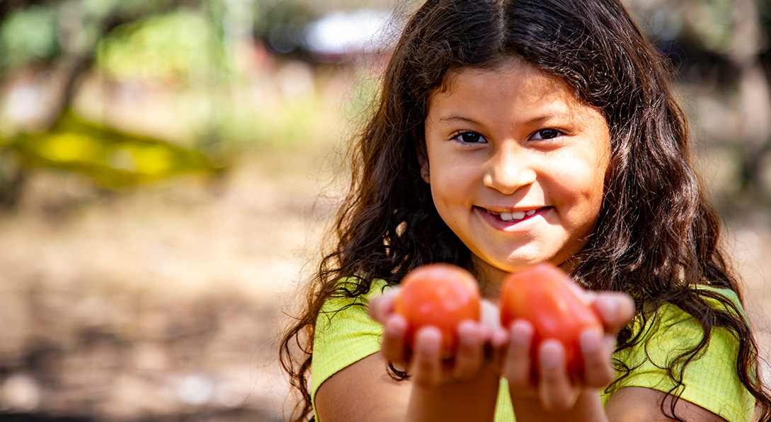 Valeria holds 2 tomatoes