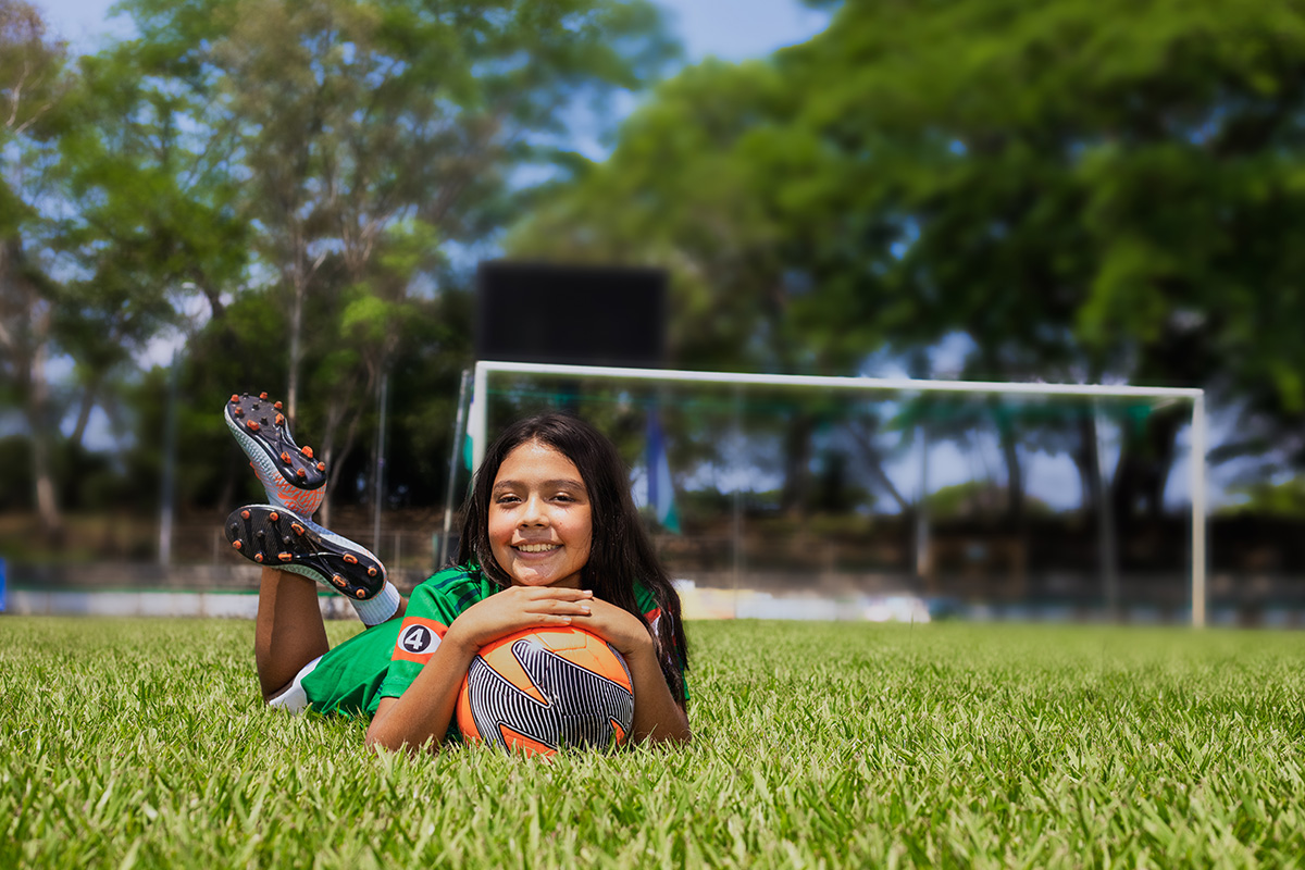 Karla lays on the field with a ball