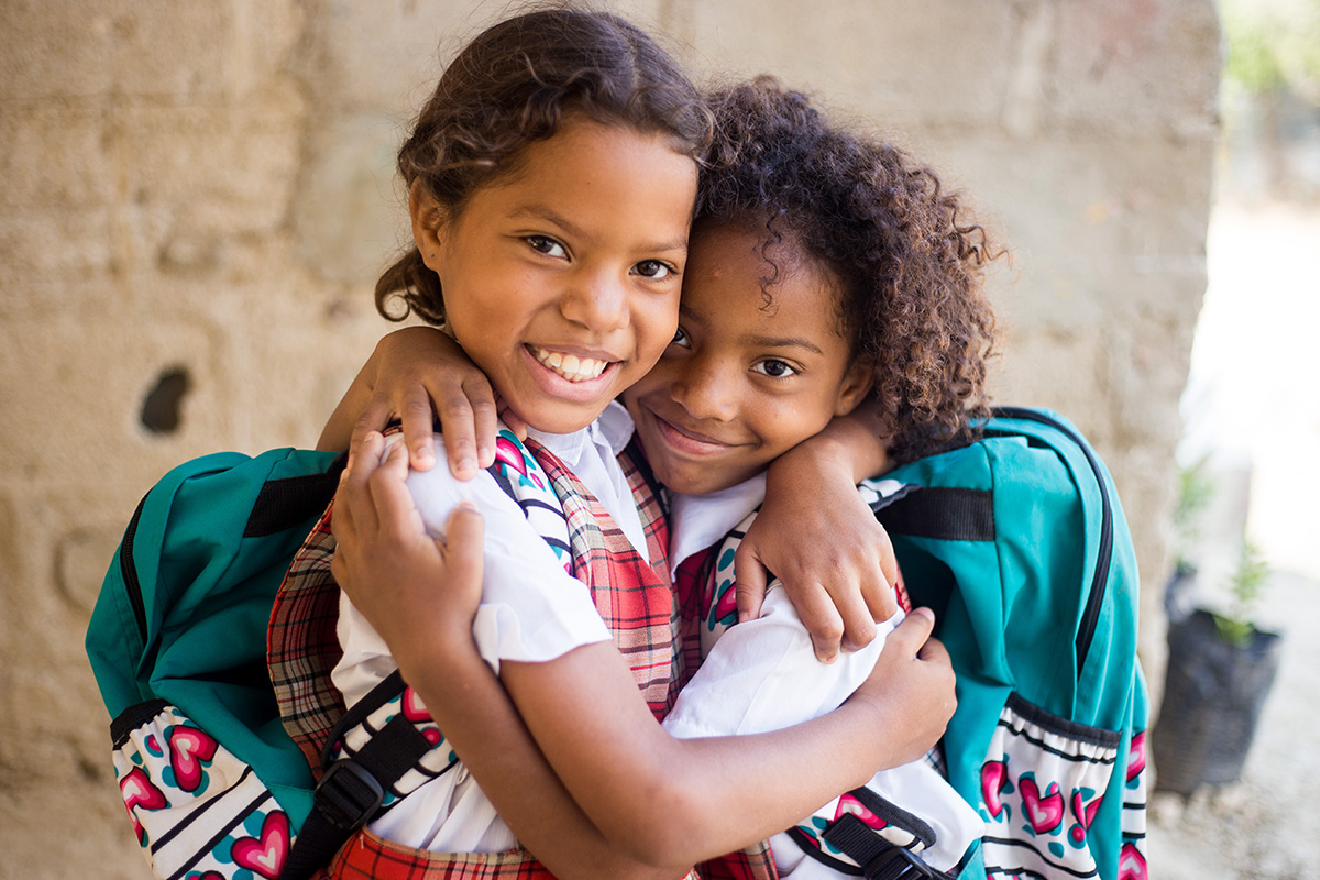 Two children hugging with backpacks on