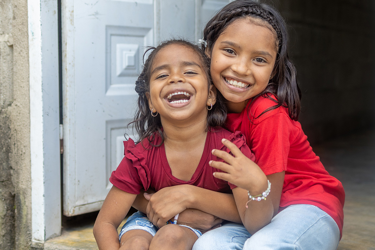 Two children hugging and smiling in front of door