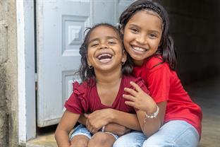 two children hugging and smiling in front of door