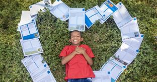 boy smiles and lies on letters shaped as a heart