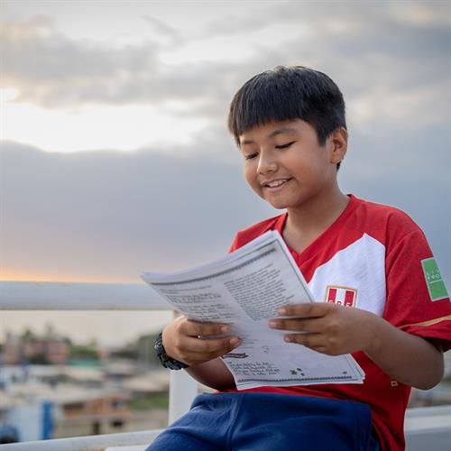 child smiles as he reads a letter