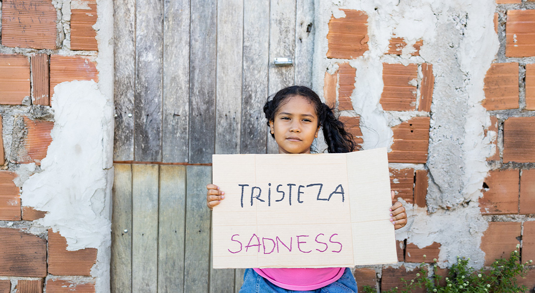 Maria holds sign that says "sadness"