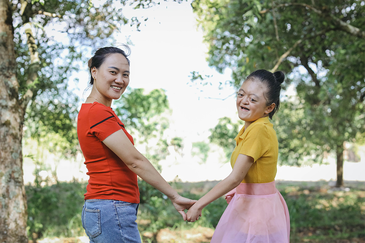 mom and daughter hold hands and smile