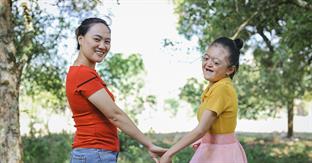 mom and daughter hold hands and smile