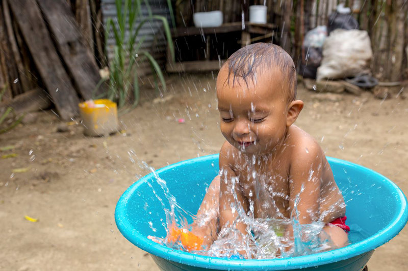 A baby boy splashes in his bathtub