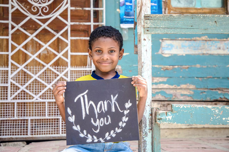 A boy holds a sign that says "Thank You"