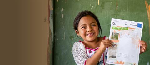 A girl stands outside near a fence