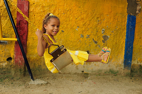 A girl in a yellow dress sits in a swing