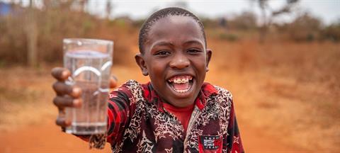 A young child holding a glass of water