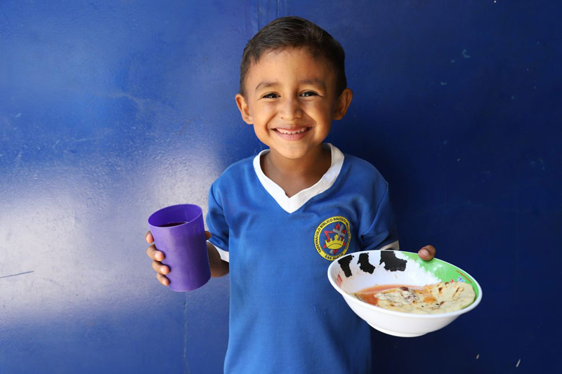 A young boy smiles as he holds a favorite traditional meal