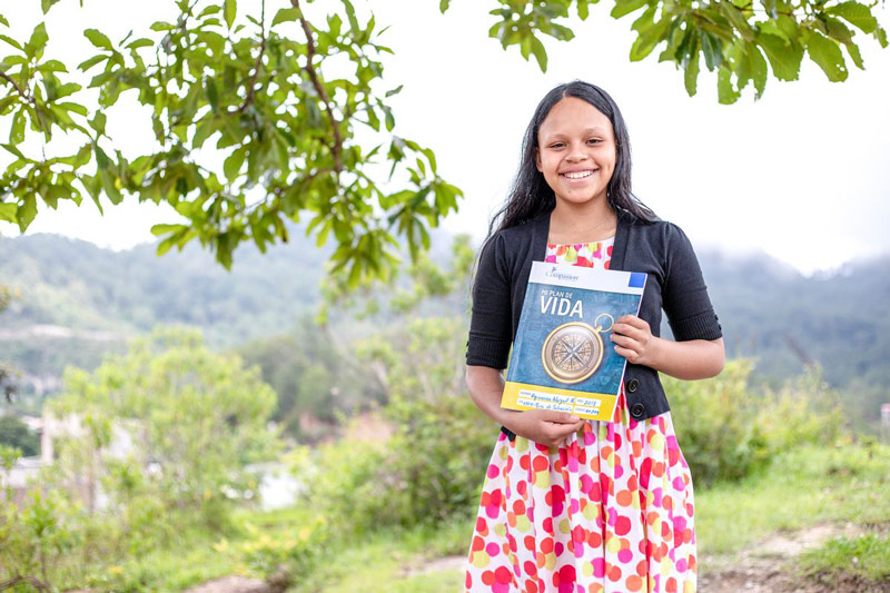 A girl holds a planning book outside of her child development center
