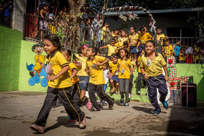 A group of kids in yellow uniforms run out of their center