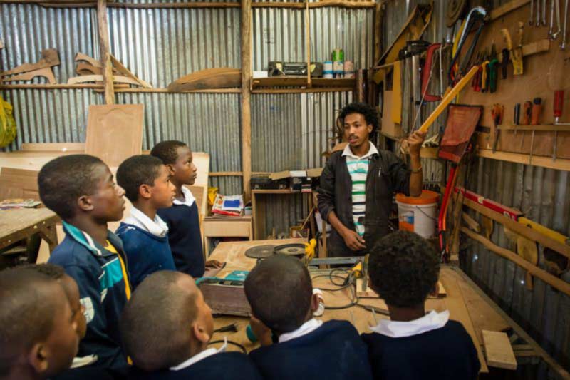 A young man teaching boys in a woodworking class