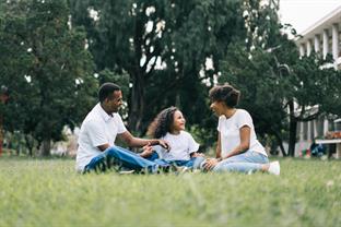 A family sits in grass and laughs