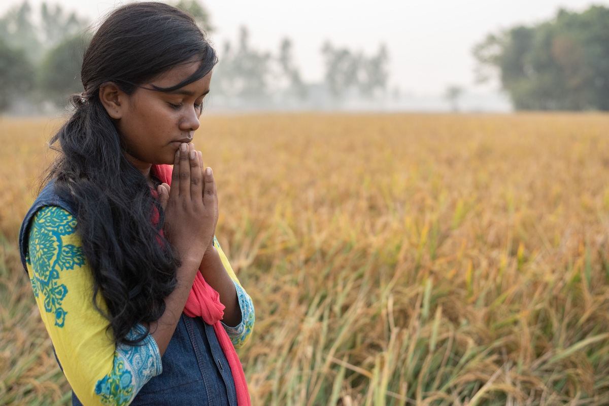 A girl praying in a field
