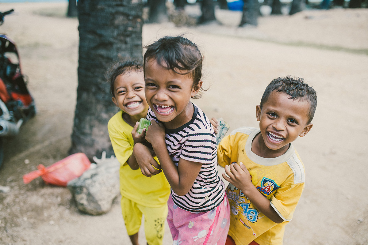 3 children in Indonesia laugh at the camera